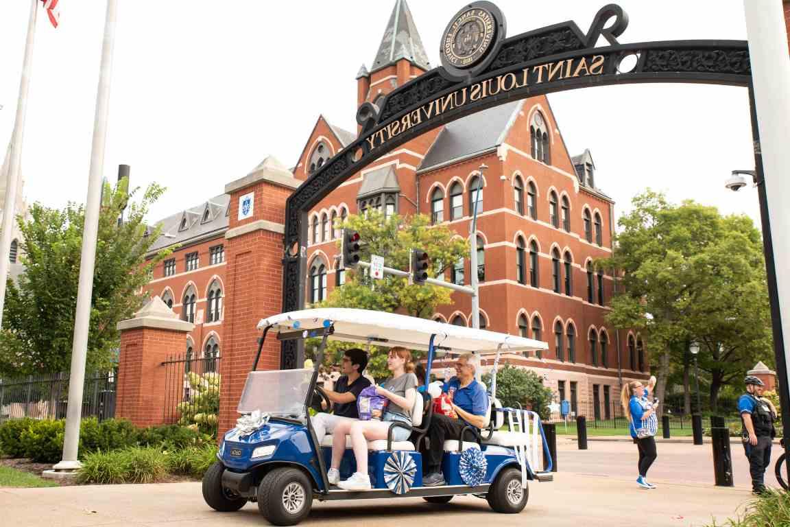 Dr Fred Pestello rides a golf cart through 博彩网址大全's archways along Grand Boulevard in the 2023 golf cart parade